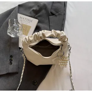 Detail of cream white pleated handbag with silver chain strap and pearl heart charm