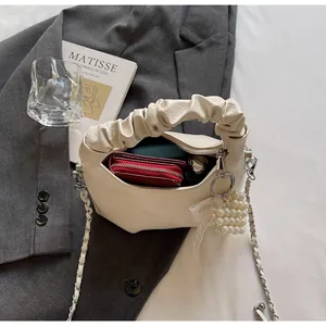 Close-up of cream pleated handbag showing pearl charm, lace bow, and storage capacity