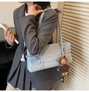 Close-up of light blue underarm bag with cute teddy bear charm and silver buckle detail