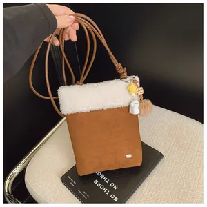 Détail du sac bandoulière en similicuir marron avec bordure en peluche et pendentifs