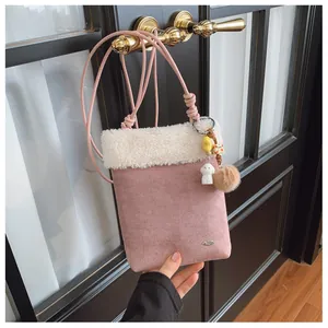 Détail du sac à bandoulière en similicuir rose avec bordure en sherpa blanc et breloques