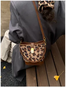 Modieuze luipaard bucket bag met gouden sluiting getoond in een herfstachtige buitenomgeving