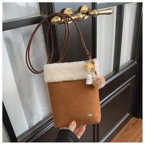 Détail d'un sac bandoulière en daim marron avec bordure en peluche blanche et des breloques