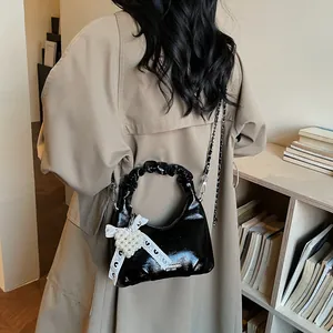Mini black patent leather crossbody bag with pleated handle and pearl heart charm