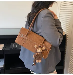 Retro brown suede shoulder bag with cute teddy bear charm on model's shoulder