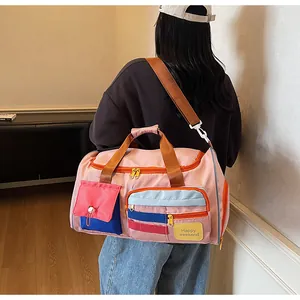Detail of pink travel bag with Happy Weekend text and adjustable shoulder strap worn by model