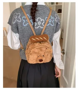 Close-up of plush brown teddy bear backpack with cute decorative baguette and metal hooks
