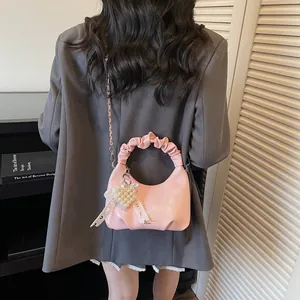 Sweet pink pleated handbag with pearl heart charm and metal chain on a female model