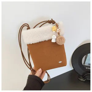 Détail d'un sac à bandoulière en daim marron avec bordure en fausse fourrure et breloques