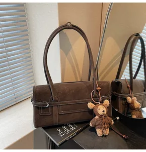 Detail of vintage brown suede shoulder bag with contrast stitching and teddy bear charm