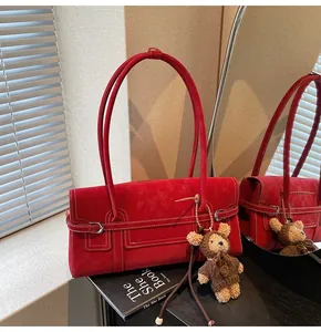 Detailed view of red plush shoulder bag with white stitching and cute bear charm