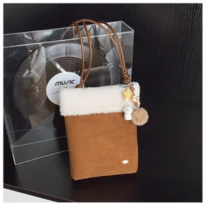 Détail du petit sac carré en daim caramel avec bordure en peluche et breloques étoiles