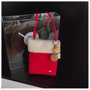 Détail du sac bandoulière d'hiver en peluche rouge avec bordure blanche et jolis charmes