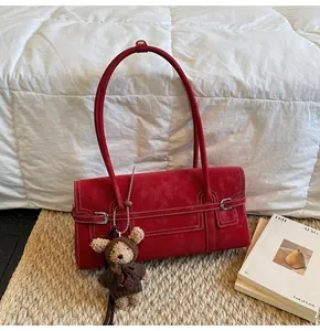 Detail of red rectangle shoulder bag with white stitching and plush bear charm