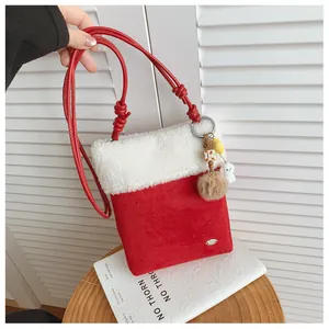 Détail du sac bandoulière en daim rouge avec bordure en peluche et pendentif mignon