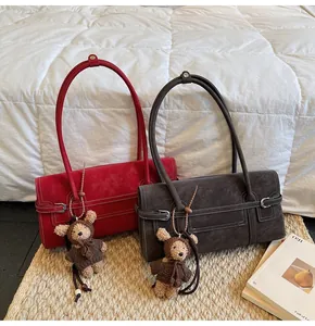 Close-up of vintage faux leather shoulder bags with white stitching and bear charm