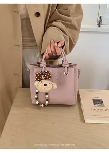 Detail of pink pebbled leather tote bag with cute plush bear charm and beaded tassel
