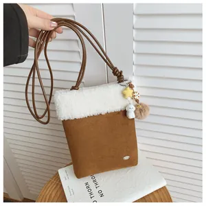 Détail d'un sac bandoulière en daim marron avec bordure en peluche blanche et breloque