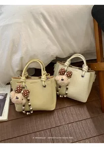 Detail of mini bucket bags in yellow and beige lychee leather with cute bear charms