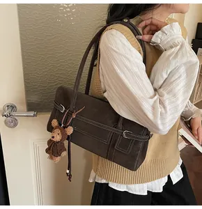 Detail of dark brown vintage shoulder bag with contrast stitching and teddy bear charm