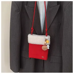 Détail du sac à bandoulière d'hiver en daim rouge avec peluche blanche et pendentifs