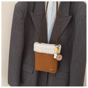 Détail d'un petit sac à bandoulière en daim marron avec bordure en peluche blanche