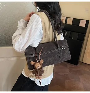 Close-up of retro brown shoulder bag with metal buckle and teddy bear plush charm