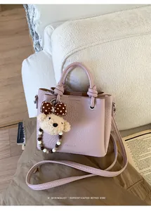 Detailed shot of a purple lychee leather bucket bag with a cute bear charm and bow