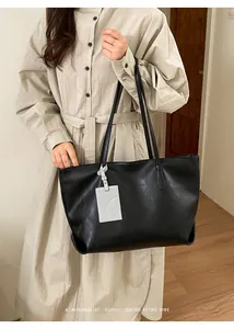 Close-up of black leather tote bag with unique cat-embossed charm and minimalist texture