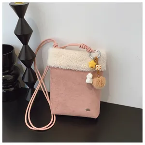 Détail du sac à bandoulière rose en daim avec bordure en peluche et pendentif décoratif