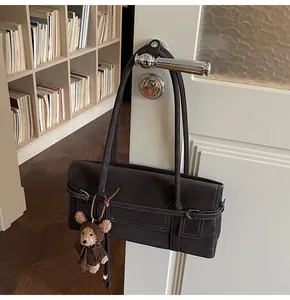 Detail of vintage tote bag with contrast stitching and cute bear charm on door handle