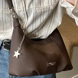 Borsa a mezzaluna marrone scuro in pelle con ciondolo a stella indossata dal modello