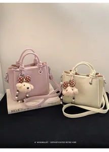 Detail of pink and beige mini bucket bags with knotted handles and teddy bear charm