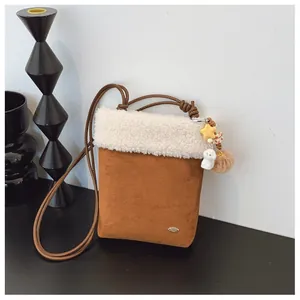 Détail du sac bandoulière en daim marron avec bordure en peluche blanche et breloques étoile