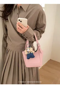 Roze bucket bag van leer met lychee-textuur en schattige beer hanger aan een model