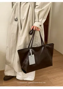 Deep brown oversized tote bag with vintage leather texture and cute animal pendant detail