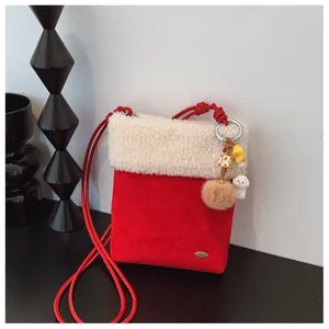 Détail du sac à bandoulière en peluche rouge avec bordure blanche et breloque chien