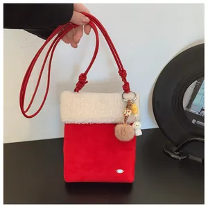 Détail du sac bandoulière en daim rouge avec bordure en peluche et porte-clé chien