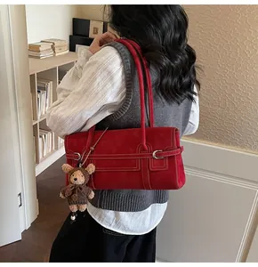 Detail of red faux suede underarm bag with contrast stitching and bear keychain charm