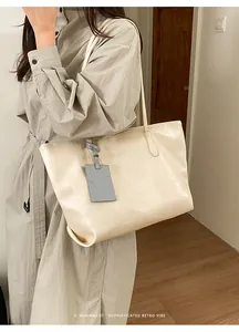 Detailed view of the large cream tote bag with elegant gray embossed pet tag decoration