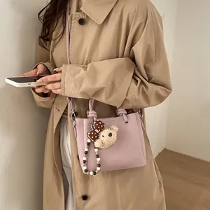 Fashionable lavender crossbody bucket bag with bear charm and pebbled leather finish