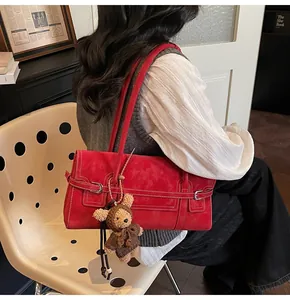 Detail of red suede tote bag with white contrast stitching and cute teddy bear charm
