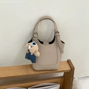 Beige lederen emmertas met berenhanger voor modieuze herfststyling