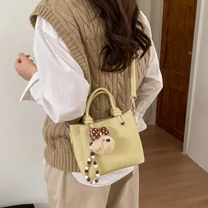 Chic yellow lychee leather tote bag with fashion text and cute bear charm pendant