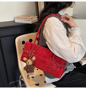 Detail of red vintage shoulder bag with silver buckle and cute knitted bear charm