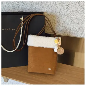 Détail du sac bandoulière d'hiver en daim marron avec bordure en fausse fourrure blanche