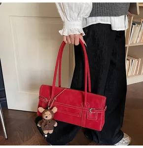 Detail of red vintage suede shoulder bag with contrast stitching and bear charm