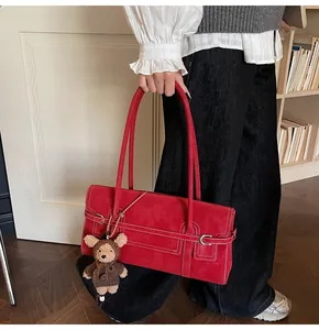 Detail of red shoulder bag with white contrast stitching and a small brown bear charm