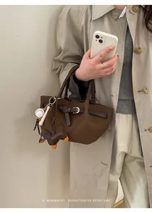 Detailansicht der braunen Leder-Einkaufstasche mit Baseball-Anhängern und Dackel-Puppe