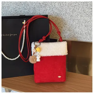 Gros plan du sac à bandoulière en peluche rouge avec bordure en laine blanche et pendentifs